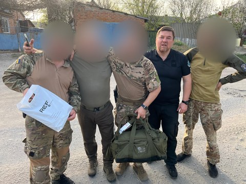 Група людей із пакунками; частину облич приховано.